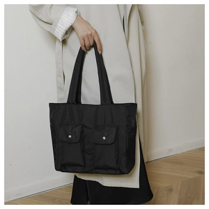 Detail of black nylon tote bag with silver snap button pockets for daily student commute
