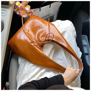 Detail of the caramel patent leather tote bag with bow accent and glossy texture