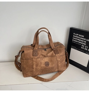 Dettaglio della borsa da viaggio in pelle sintetica marrone vintage su marmo bianco