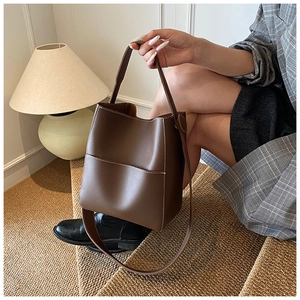 Détail du sac seau marron foncé avec coutures blanches contrastées et double bandoulière