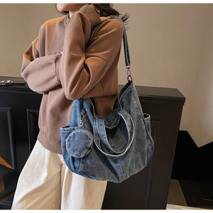 Detail of blue denim tote bag with circular coin purse shown on a model's shoulder