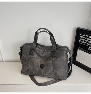 Dettaglio borsa da viaggio grigia vintage con logo in pelle e manici doppi rinforzati