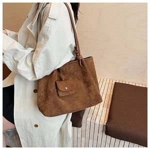 Side view of a large brown matte tote bag worn with a beige trench coat for a chic style