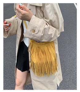 Detail of yellow suede fringe crossbody bag with bohemian tassel and crescent shape design