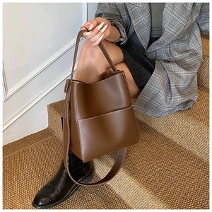 Vue détaillée du sac seau en cuir marron avec surpiqûres blanches et poche latérale
