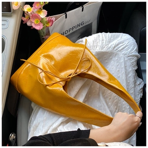 Detail view of bright yellow patent leather tote bag with bow tie knot decoration