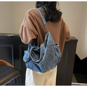 Detail of blue denim tote bag with round coin purse worn by model in casual outfit