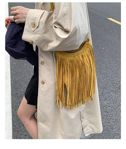 Detail of bohemian ginger yellow fringe shoulder bag with suede texture in outdoor setting
