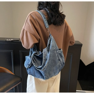Detail of a large denim tote bag with a matching mini round pouch on a fashion model