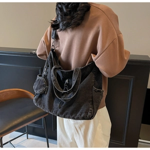 Detail of large black denim tote bag with round coin purse on a shoulder model