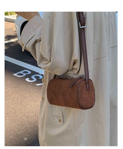 Detail of brown suede cylinder shoulder bag showing matte texture and silver hardware finish