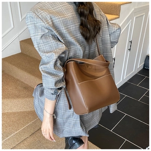 Détail du sac seau en cuir marron avec surpiqûres contrastées et poche frontale pratique