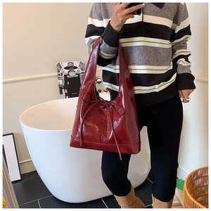 Detail view of burgundy patent leather tote bag with a minimalist bow decoration