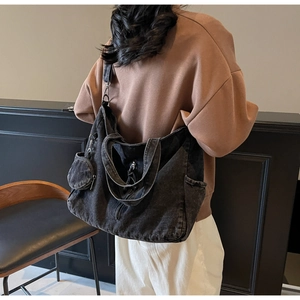Detailed back view of a large black denim tote bag with round coin purse and shoulder strap