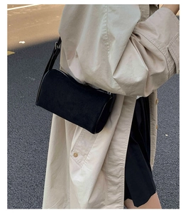 Outdoor street style view of a black matte underarm bag with silver zipper detail
