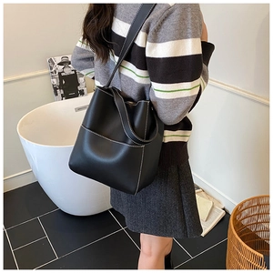 Détail du sac seau en cuir noir avec surpiqûres blanches et large bandoulière en cuir