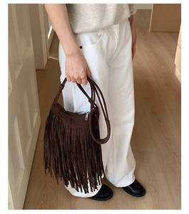 Detailed close-up of dark brown bohemian fringe bag with soft suede texture and tassels