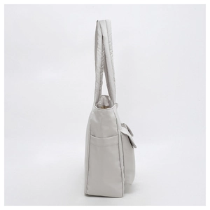 Detail view of large canvas tote bag showing quilted shoulder straps and side pockets