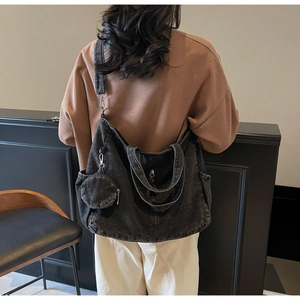 Rear view of model wearing a large washed denim tote bag with a mini round coin purse