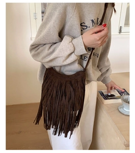 Detail of dark brown leather crossbody bag with long fringe tassels and slim strap