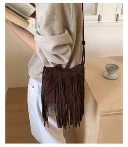 Detail of dark brown suede fringe bag with long decorative tassels and shoulder strap