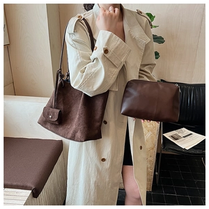Detail of vintage matte tote and leather pouch on a model wearing a beige trench coat