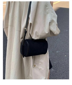 Detail of minimalist black cylindrical crossbody bag with matte finish and leather strap