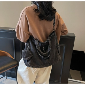 Detailed view of black washed denim tote bag with round hanging charm on the shoulder strap