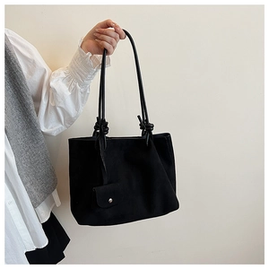 Detail of black matte tote bag featuring knotted shoulder straps and mini coin purse attachment