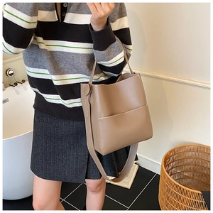 Détail du sac seau kaki avec coutures contrastées et longue bandoulière sur mannequin
