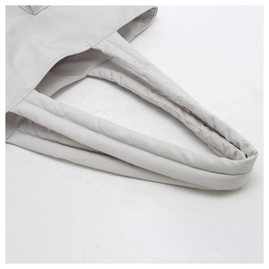 Close-up of padded handles on a large grey canvas tote bag with smooth nylon texture