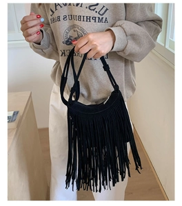 Close-up detail of black bohemian tassel bag with suede texture and metal zipper