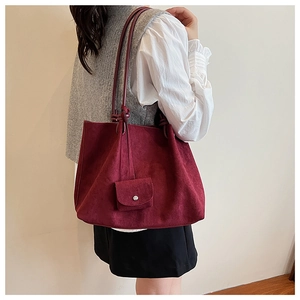 Close-up of a burgundy suede tote bag with a small pouch and matching cord straps