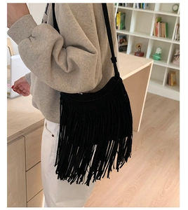 Detail of black bohemian tassel shoulder bag showing long fringe and suede texture
