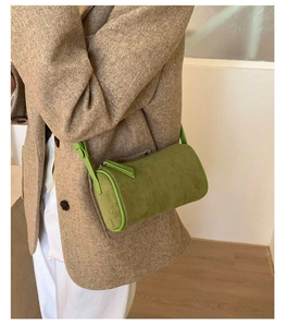 Fashionable green cylinder bag in matte texture styled with a tweed blazer on a model