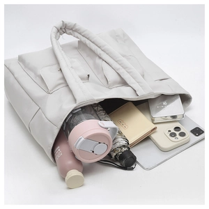 Large quilted tote bag with front pockets showing laptop, umbrella, and daily items inside