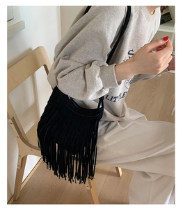 Detailed view of bohemian black fringe crossbody bag with suede texture and tassels