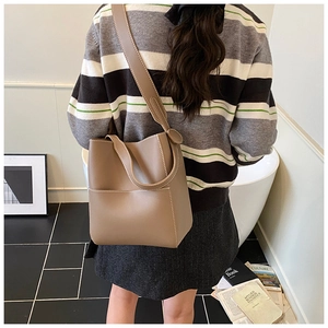 Détail du sac seau en cuir gris éléphant avec surpiqûres blanches et bandoulière large