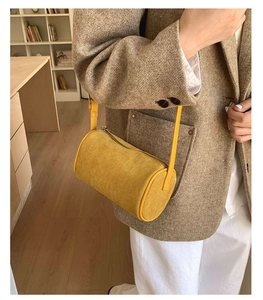 Detail of a bright yellow suede shoulder bag paired with a stylish brown wool blazer
