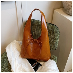 Detail view of brown vintage tote bag with bow accent on a green tweed chair