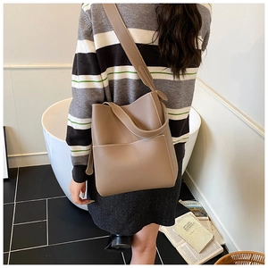 Detail of tan bucket bag with white contrast stitching and a wide shoulder strap