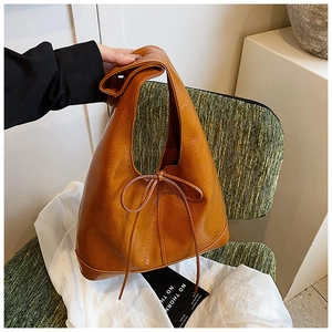 Detailed view of caramel patent leather tote bag with a decorative bow and soft texture
