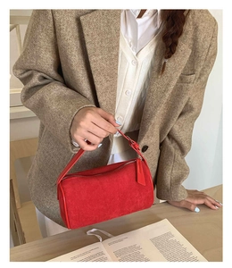 Close-up of a vibrant red frosted suede cylindrical bowling bag with smooth leather straps