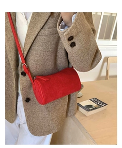 Detail of red cylindrical suede crossbody bag styled with a beige herringbone blazer