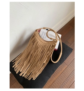 Detail of light brown bohemian crossbody bag with long tassels and suede texture