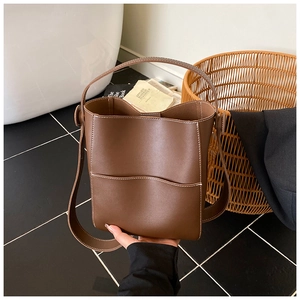 Gros plan détaillé du sac seau marron avec surpiqûres blanches et poche avant ouverte