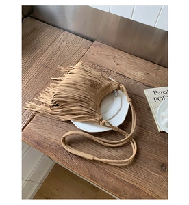 Detailed top view of a brown suede bohemian crossbody bag with long tassel fringe on wood