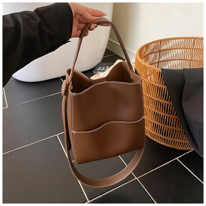 Détail du sac seau en cuir marron avec surpiqûres blanches et poche ondulée