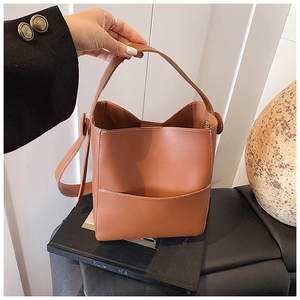 Détail d'un sac seau en cuir marron caramel avec surpiqûres blanches et bandoulière réglable