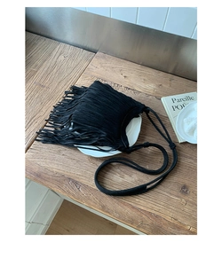 Detail of bohemian black fringe bag on wooden surface with vintage decorative items